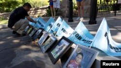 Jose Badillo places March for Our Lives flags behind portraits of some of the victims of the Robb Elementary School shooting during a "March for Our Lives" rally in Austin, Texas, June 11, 2022.