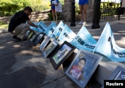 Jose Badillo menempatkan bendera March for Our Lives di belakang potret beberapa korban penembakan di Sekolah Dasar Robb selama demonstrasi "March for Our Lives" di Austin, Texas, 11 Juni 2022. (Foto: Reuters)