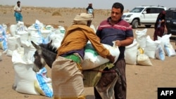 FILE - Poor Yemeni families receive flour rations and other basic food supplies from charities in the province of Lahj, in southern Yemen, March 29, 2022. The fact that Ukraine supplies nearly a third of Yemen's wheat imports has heightened fears of a deepening famine.