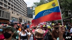 Milicianos bolivarianos, simpatizantes del gobierno y trabajadores estatales participan en una marcha para brindar su apoyo al presidente venezolano Nicolás Maduro, quien se encuentra en una gira internacional por países asiáticos y europeos, en Caracas, el 9 de junio de 2022.