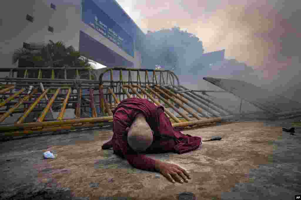 A Buddhist nun falls next to a barricade after inhaling tear gas during a protest outside police headquarters in Colombo, Sri Lanka.