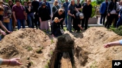 Relatives of Army Col. Oleksander Makhachek mourn during his funeral in Zhytomyr, Ukraine, June 3, 2022.