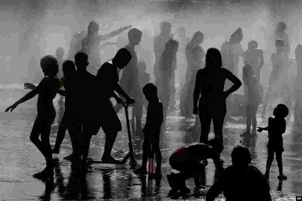 Children and adults cool off in a fountain in a park by the river in Madrid, Spain, June 12, 2022.&nbsp;Spain&#39;s weather service says temperatures are expected to rise to 43&deg;&nbsp;C in certain areas.&nbsp;(AP Photo/Paul White)