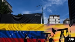 Un hombre con cubrebocas pasa frente a un mural que representa una bomba de aceite y la bandera venezolana en una calle de Caracas, el 26 de mayo de 2022. 