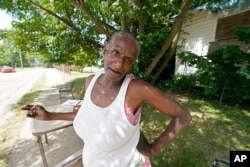 Linda Collier stands under a shade tree near her home in Jackson, Mississippi, to find some relief from temperatures in the 90s, June 13, 2022. Heat advisories, excessive heat warnings and excessive heat watches were issued over states stretching through parts of the Gulf Coast to the Great Lakes and east to the Carolinas.