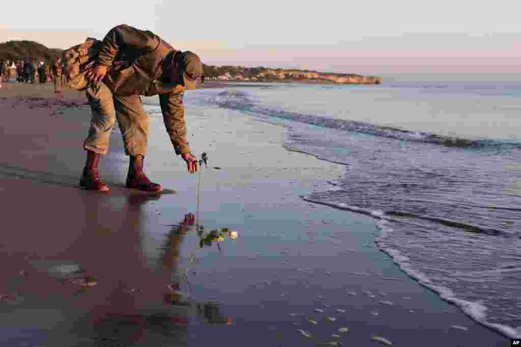 World War II reenactor places roses on Omaha Beach, in Saint-Laurent-sur-Mer, Normandy, France, the day of 78th anniversary of the assault that helped bring an end to World War II.