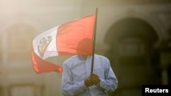 ARCHIVO - Un ciudadano enarbola una bandera de Perú durante las protestas del año pasado en Lima, en abril de 2022.