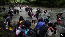 (FILE) Migrants cross a river during their journey through the Darien Gap from Colombia into Panama, hoping to reach the U.S., Oct. 15, 2022.