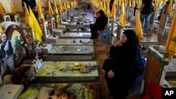 Women sit in a cemetery as they visit the graves of killed Hezbollah members in the southern suburbs of Beirut, Sept. 19, 2024.