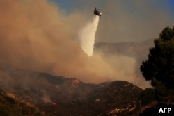 A helicopter drops water as the Franklin Fire grows in Malibu, California, on Dec. 10, 2024.