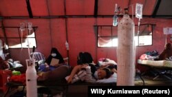 Seorang pasien COVID-19 terbaring di atas velbed di tenda sementara di luar ruang gawat darurat rumah sakit pemerintah di Bekasi, 25 Juni 2021. Awal pekan ini pasokan oksigen medis di Jawa Tengah dan Yogyakarta sempat terganggu. (Foto: REUTERS/Willy Kurniawan)