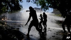 Protesters throwing stones at police are sprayed by water cannons during a general strike against a pension reform measure, outside Congress in Buenos Aires, Argentina, Dec. 18, 2017.