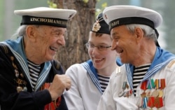 FILE - World War II veterans share a joke, as a boy wearing a navy uniform listens, during a Victory Day celebration in Gorky Park in Moscow, May 9, 2012.