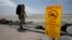 FILE - A beachgoer walks past a sign posted to warn people of contaminated water at Torrey Pines State Beach in San Diego, California.