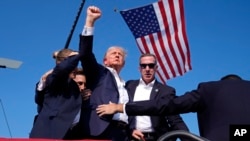 Mantan Presiden AS Donald Trump mengacungkan tinju saat dievakuasi dari panggung kampanye usai insiden penembakan, di Butler, Pennsylvania, Sabtu, 13 Juli 2024. (Foto: Evan Vucci/AP Photo)