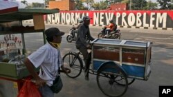 Para penjaja makanan jalanan melintas di depan mural di tengah pandemi virus corona di Jakarta, 8 Juni 2020. (Foto: Reuters)