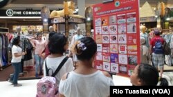 Pengunjung memperhatikan pengumuman diskon jari ungu di pusat perbelanjaan Kota Kasablanka, Jakarta, Rabu,17 April 2019. (Foto: Rio Tuasikal/VOA)