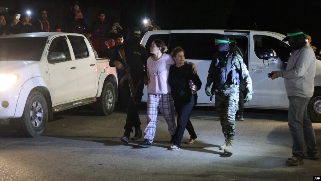 Các chiến binh Hamas và Hồi giáo Jihad đi cùng các con tin Israel mới được thả, bị giam giữ kể từ cuộc tấn công ngày 7 tháng 10 của Hamas, trước khi giao họ cho Hội Chữ thập đỏ ở Rafah, phía nam Dải Gaza vào ngày 28 tháng 11 năm 2023.