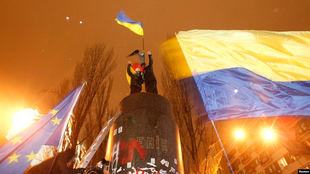 People climb up to the top of a pedestal after a statue of Soviet state founder Vladimir Lenin was toppled by protesters during a rally organized by supporters of EU integration in Kyiv, December 8, 2013.