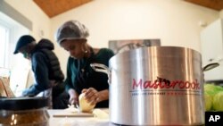 Chief coordinator Glenda Andrew, centre and volunteer Dave Williams prepare West Indian meals with members of the Preston Windrush Covid Response team, at the Xaverian Sanctuary, in Preston, England, Feb. 19, 2021.