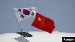 FILE - Flags from South Korea, left, and China flutter atop an aircraft at Beijing Capital International Airport in China, Sept. 2, 2015.