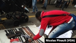 Un vendeur sénégalais installe sa marchandise au marché de Lima, Milan, 10 octobre 2015 (Nicolas Pinault/VOA)