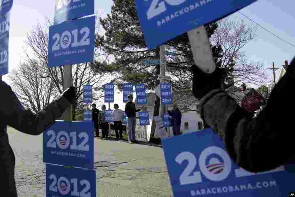 Supporters of President Barack Obama hold signs near a campaign stop for Republican presidential candidate, former Massachusetts Gov. Mitt Romney in Portsmouth, New Hampshire, April 30, 2012. (AP)