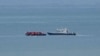 FILE - A boat thought to be carrying migrants is escorted by a vessel from the French Gendarmerie Nationale in the English Channel off Wimereux beach, France, Sept. 4, 2024. 