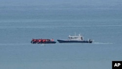 FILE - A boat thought to be carrying migrants is escorted by a vessel from the French Gendarmerie Nationale in the English Channel off Wimereux beach, France, Sept. 4, 2024. 