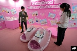 Visitors react to gigantic Hello Kitty slippers at the exhibition "As I change, so does she," marking the 50th anniversary of Hello Kitty at the Tokyo National Museum in Tokyo, Oct. 30, 2024.