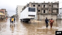 Les gens traversent le quartier inondé de Keur Massar, à Dakar, le 20 août 2021.