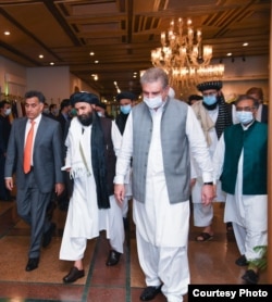ملا عبد الغنی برادر (درمیان میں) کی پاکستان آمد پر وزیر خارجہ شاہ محمود قریشی (دائیں جانب) اور خفیہ ادارے انٹر سروسز انٹیلی جنس (آئی ایس آئی) کے سربراہ لیفٹننٹ جنرل فیض حمید (بائیں جانب) نے استقبال کیا تھا۔ (فائل فوٹو)