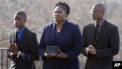 FILE - Isatu Salia carriers the cremated remains of her husband, Ebola victim Dr. Martin Salia, while their sons Maada Martin Salia, 20, right, and Hinwaii Sakatty Salia, 12, walk with her to enter St. Mary's Church in Landover Hills, Md., for a funeral Mass, Nov. 29, 2014.