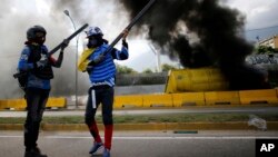 Demonstrators stand near a burning truck used as a barricade during a protest on the Francisco Fajardo highway outside La Carlota Air Base in Caracas, Venezuela, June 23, 2017.