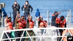 Migrants wave and give the v-sign as they disembark at Hay Wharf, Pieta, Malta, Jan. 9, 2019. 