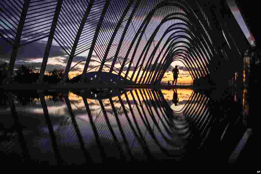 A man runs on a walkway of steel vaults, called the Agora, at the Athens Olympic Stadium complex as the sun sets in Greece. The government put in place a second nationwide lockdown on November 7, following a major rise in COVID-19 cases.