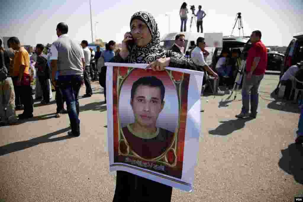 A woman holds a sign with the image of a slain protester in front of a courthouse in Cairo awaiting a verdict in the trial of former Egyptian president Hosni Mubarak, June 2, 2012. (VOA/Y. Weeks)