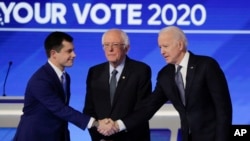 From left, former South Bend Mayor Pete Buttigieg, shakes hands with former Vice President Joe Biden as Sen. Bernie Sanders, I-Vt., watches, Feb. 7, 2020, before the Democratic presidential primary debate at Saint Anselm College in Manchester, N.H.