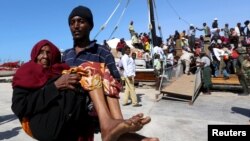 Un homme porte une vieille femme qui a débarqué d'un bateau transportant des déplacés qui fuient les violences au Yémen, au port de Bosaaso dans la région somalienne de Puntland, jeudi 16 avril 2015.