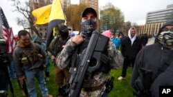 Seorang demonstran membawa senjata di gedung State Capitol, di Lansing, Michigan, 30 April 2020.