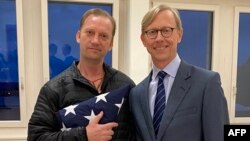 This photo released by the U.S. State Department shows Navy veteran Michael White, left, posing with Special Envoy to Iran Brian Hook at Zurich Airport in Zurich, Switzerland, June 4, 2020, after White was released from Iran.