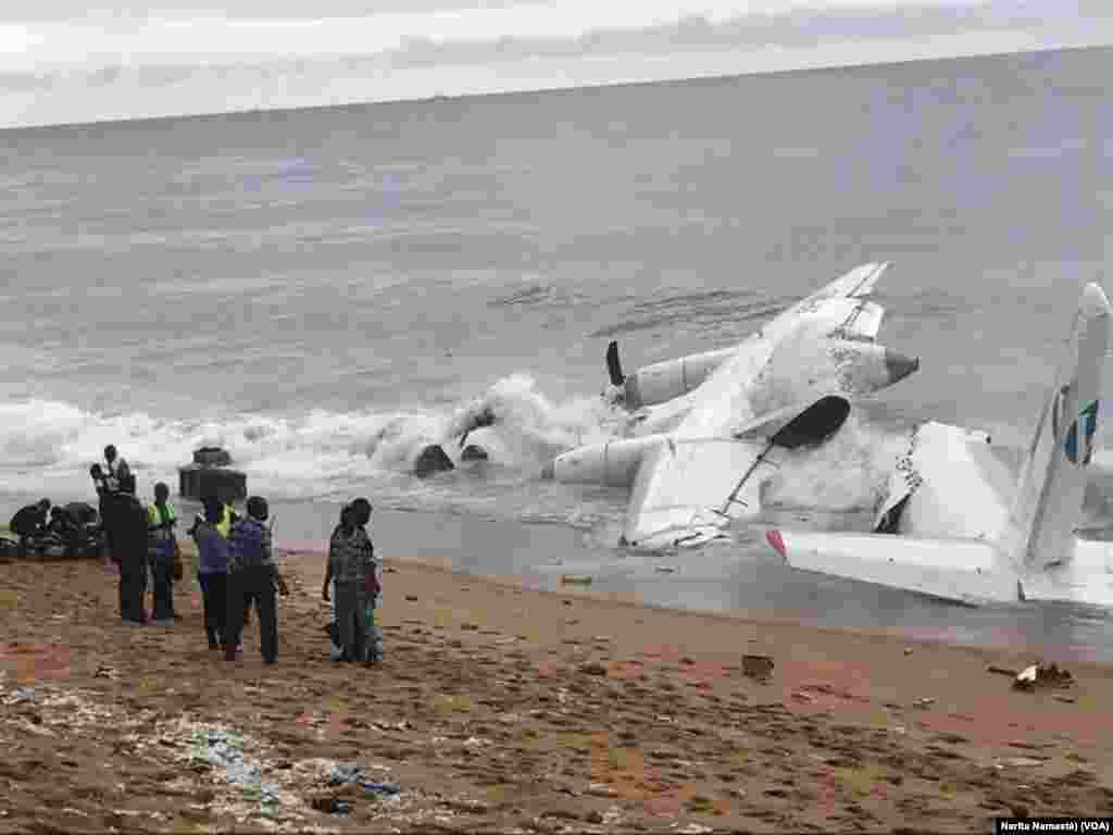 Quelques personnes près de l’épave d’avion abîmée au bord de la mer au Port Bouet, au large d’Abidjan, Côte d’ivoire, 14 octobre 2017. (VOA/Narita Namasté)