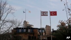 A Cypriot military guard post flies a Greek, left, and Cypriot flags next to a Turkish military guard post with Turkish, right, and Turkish Cypriot breakaway flags, between UN buffer zone, in Nicosia, Cyprus, Jan. 17, 2017. 