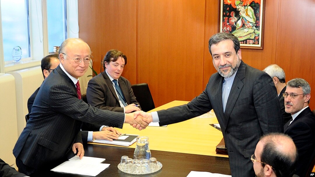 Deputi Menlu Iran, Abbas Araghchi (kanan) berjabat tangan dengan Direktur IAEA, Yukiya Amano di Wina hari Senin (28/10).