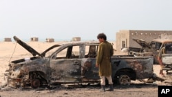 A Yemeni southern separatist fighter inspects the wreckage of government forces vehicles destroyed by UAE airstrikes near Aden, Yemen, Aug. 30, 2019. 