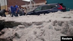 La gente quita el hielo grueso de una calle después de una granizada en medio de una ola de calor, en Puebla, México, el 24 de mayo de 2024.