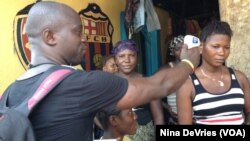 Sulaiman Watfa, an Ebola survivor, takes the temperature of resident Fatmata Bangura in the community of Moa Wharf, Sierra Leone, May 27, 2015.