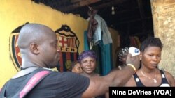 Sulaiman Watfa, an Ebola survivor, takes the temperature of resident Fatmata Bangura in the community of Moa Wharf, Sierra Leone, May 27, 2015.