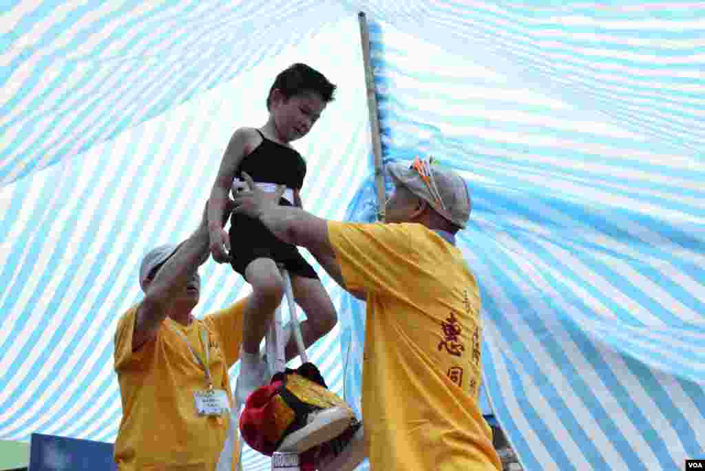 小曹星如在飄色師傅協助下坐上飄色架。(美國之音湯惠芸)