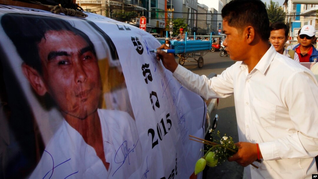 A Cambodian worker gives a signature on a poster of Chea Vichea during the 11th anniversary of assassination of Chea Vichea, former head of Cambodia's Free Trade Union of Workers, in Phnom Penh, Cambodia, Thursday, Jan. 22, 2015. (AP Photo/Heng Sinith)